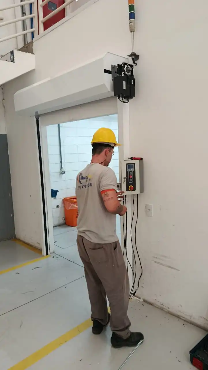 Equipe técnica certificada realizando instalação de porta rápida industrial conforme NR-12